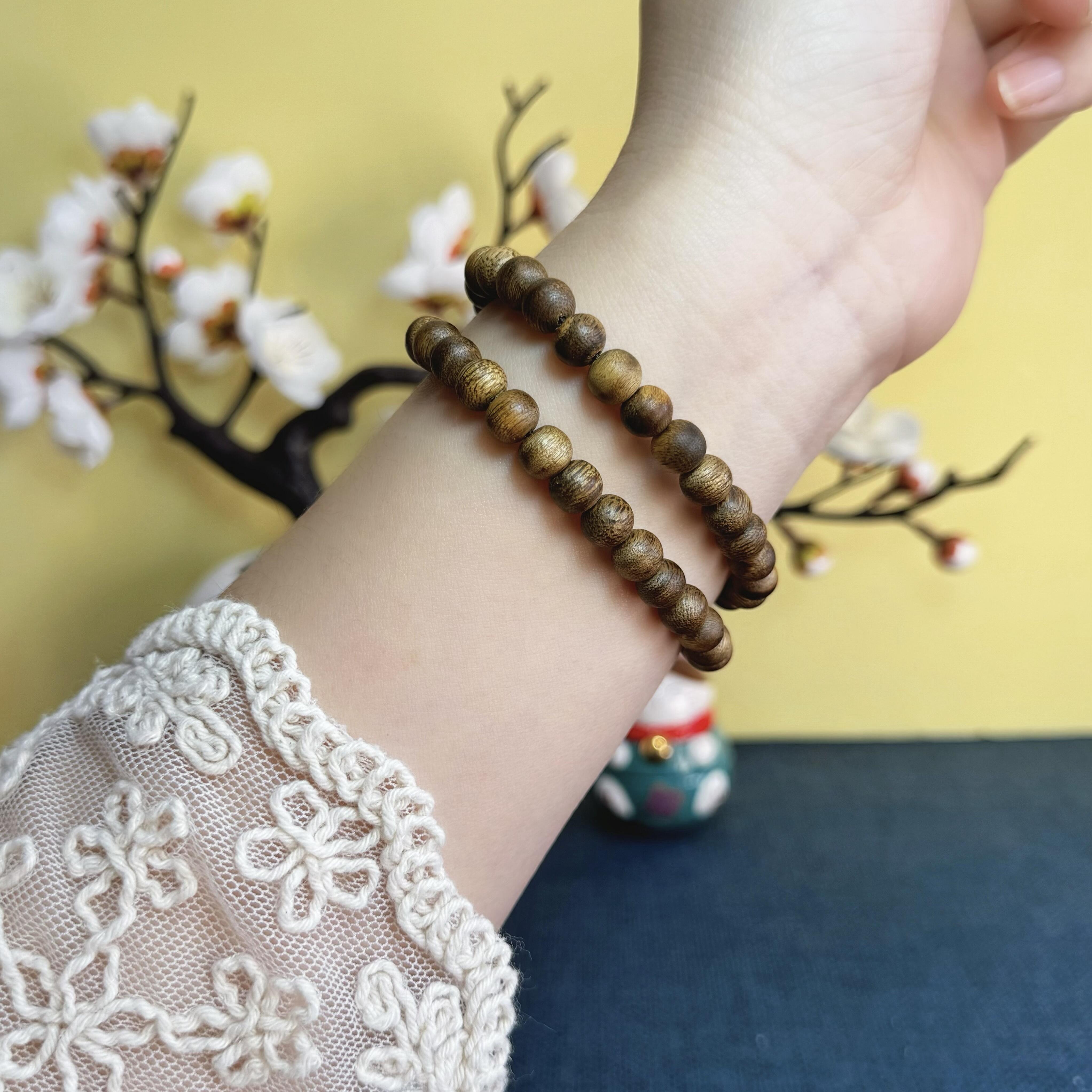 A double-wrap 7mm Hainan Yingge-Green Qinan Agarwood bracelet accented with 6mm blue-water jadeite